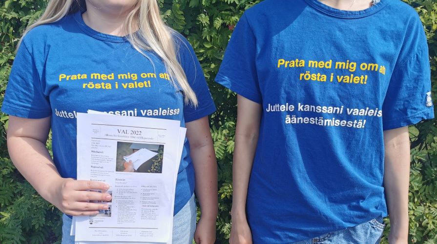 Två feriearbetare i blåa t-shirts som jobbar med att sprida information om valet 2022 och uppmanar Haparandabor att gå rösta. 