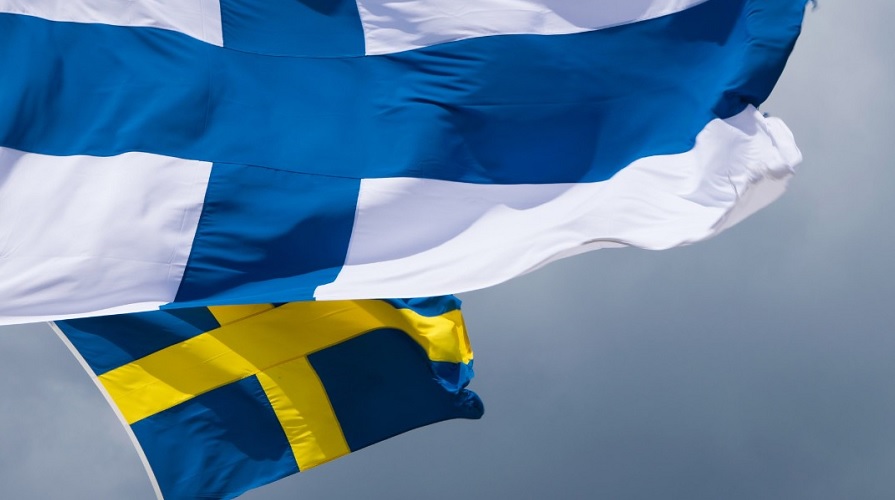 En finsk och en svensk flagga vajar i vinden.