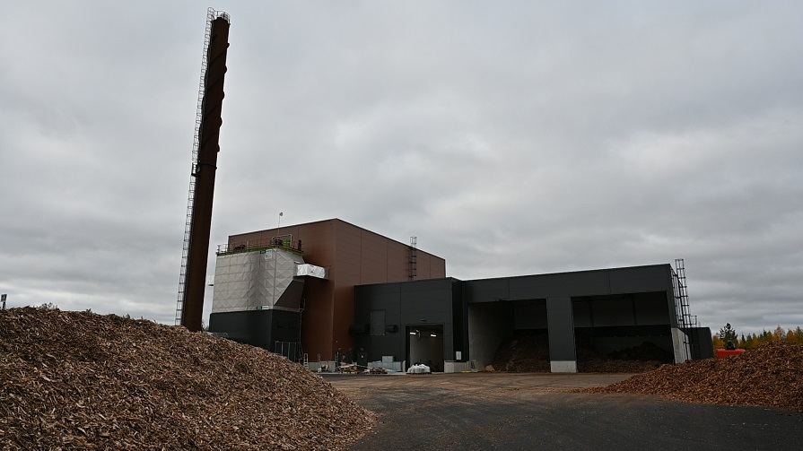 Överblicksbild på den nya fjärrvärmeanläggningen i Haparanda. I förgrunden syns högar med flis som eldas inne i anläggningen. Foto: Haparanda stad 