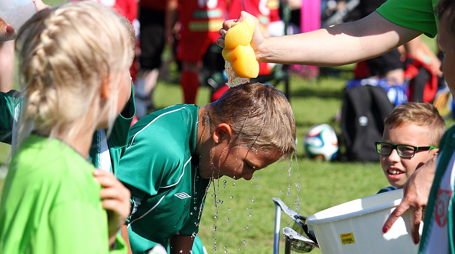 En grupp barn på en fotbollsplan vara en får vatten över huvudet.