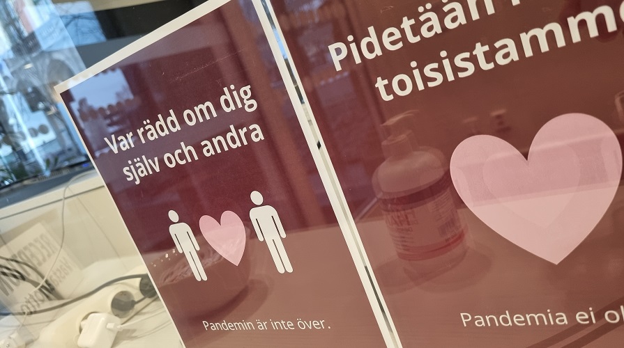 Bild på två rosa affischer med budskapet om att pandemin inte är över.