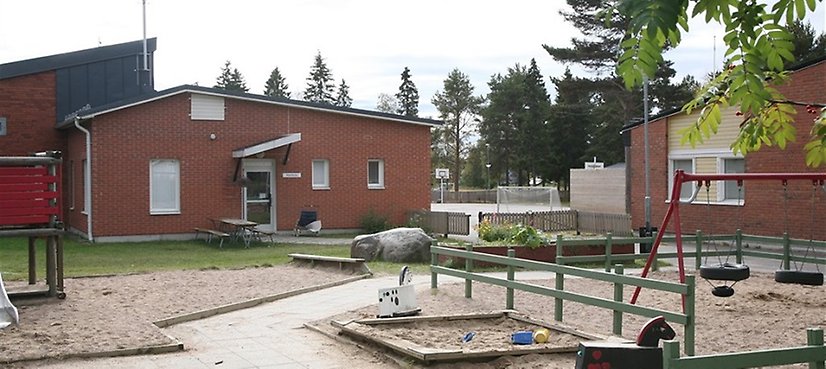 Skola samt skolgård med gungställningar och sandlåda. 