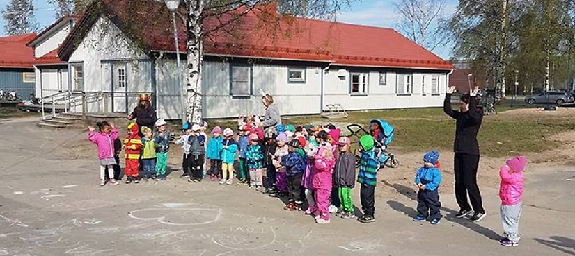 En grupp barn med lärare står utanför Montessori Droppens lokaler. 