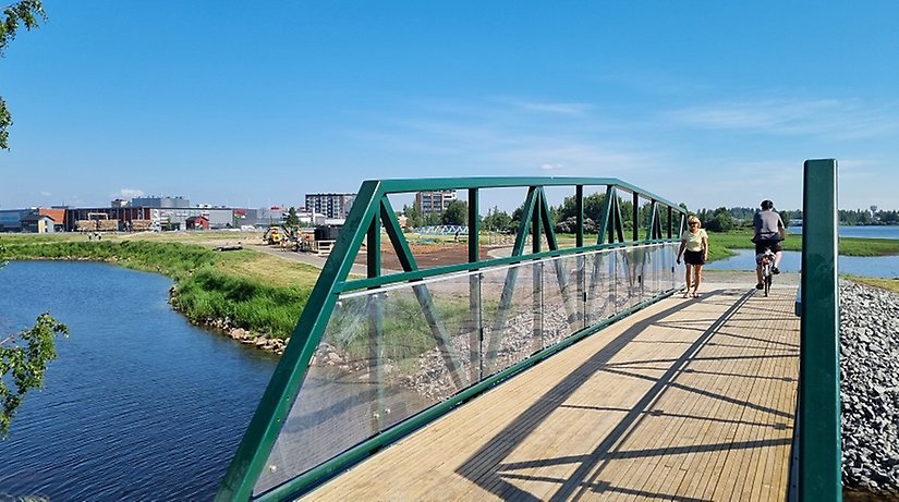 Grön gång- och cykelbro över mindre vattendrag.
