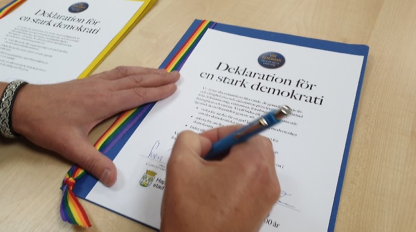 Närbild på hand med penna som skriver under ett dokument