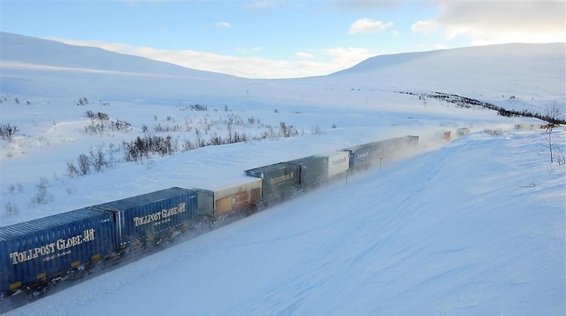 Godståg färdas genom ett snötäckt fjällandskap