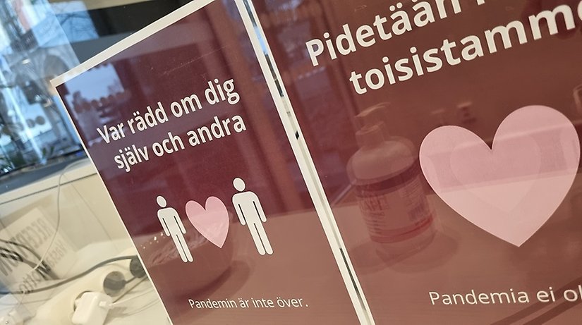 Bild på två rosa affischer med budskapet om att pandemin inte är över.