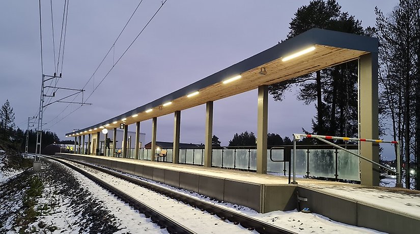 Tågspår i vinterlandskap bredvid en plattform.
